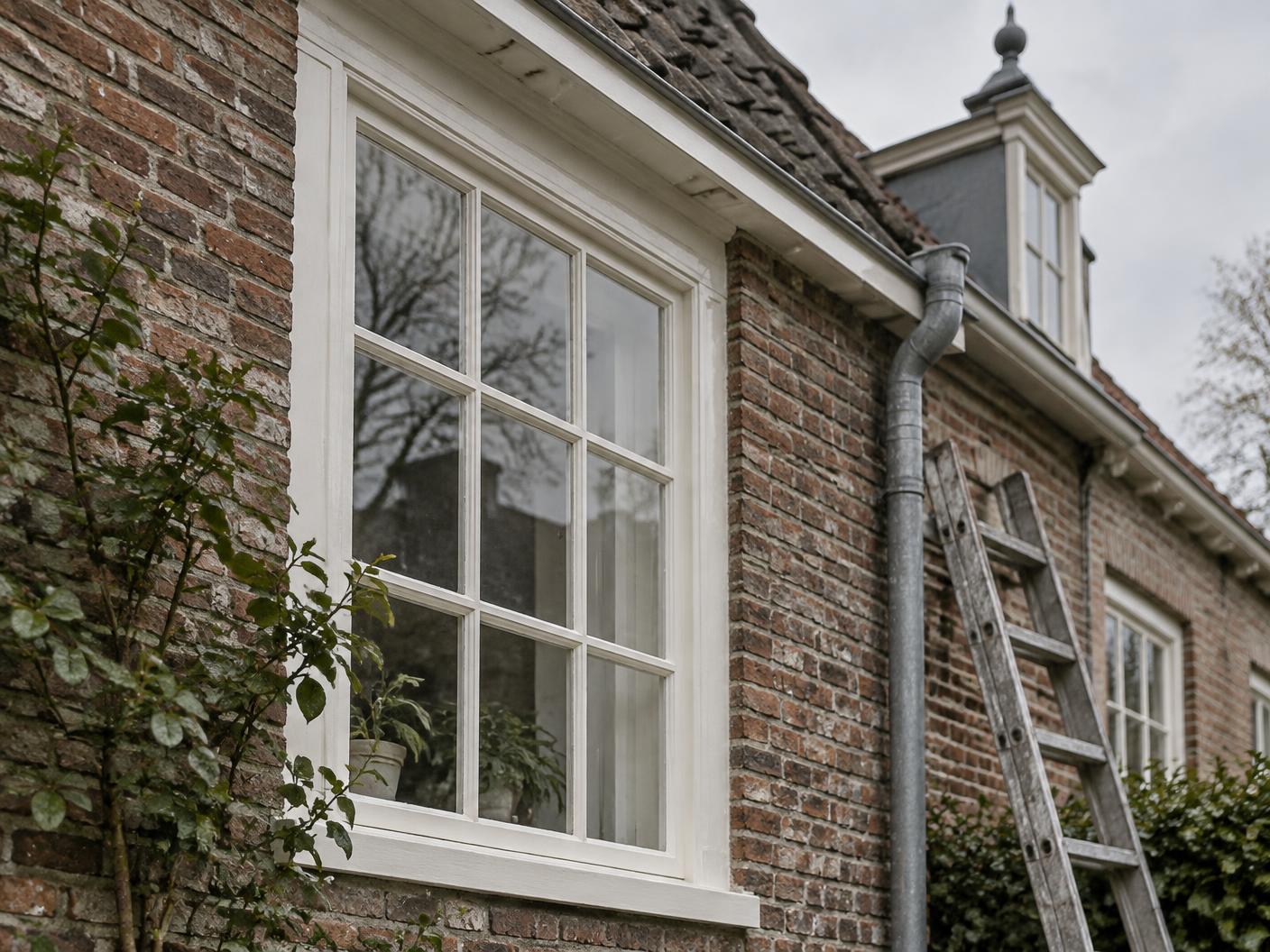 Nieuw geschilderd wit houten kozijn in een oude bakstenen gevel